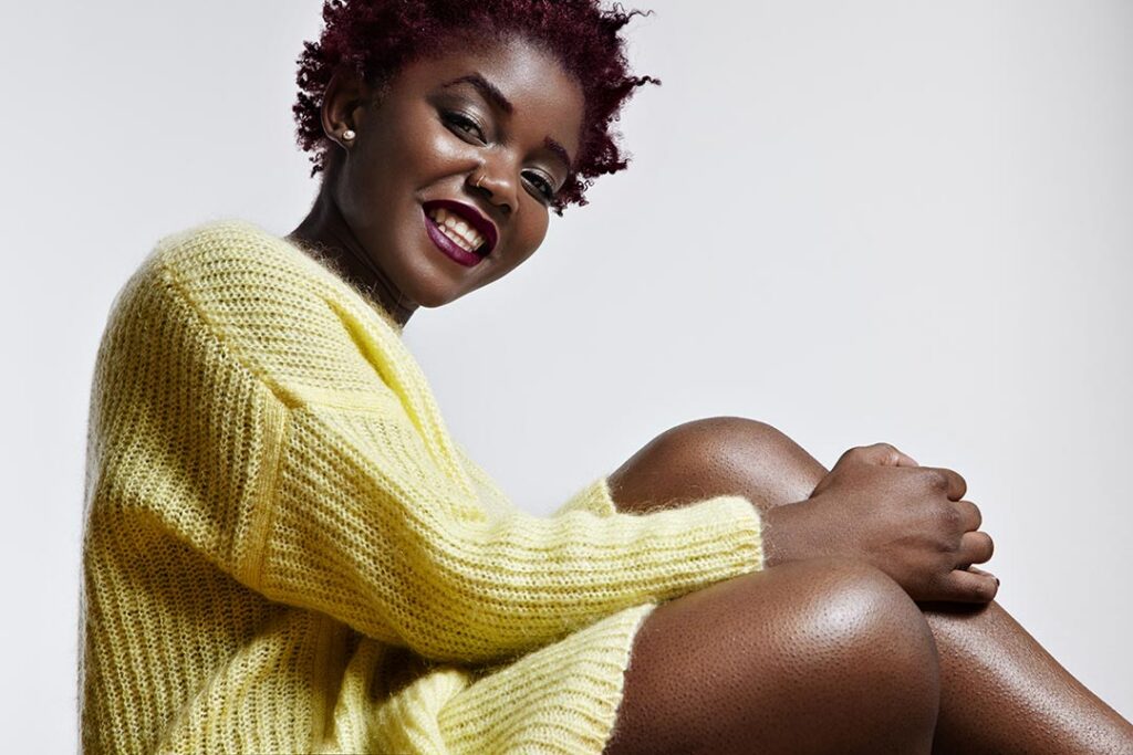 Viya health kenya shiny black woman wearing bright sweater touching her legs.jpg